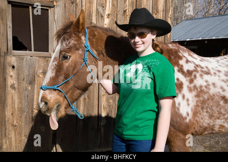 A 30 year old horse sticks out his tongue as he is petted by his teenage owner Stock Photo