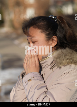Woman blowing her nose outdoors in winter