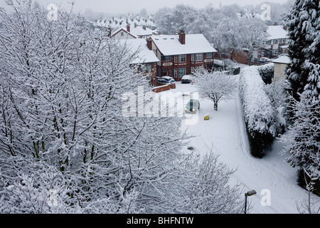 A car rounds a corner in a snow covered village viewed from a high bridge in the early morning Stock Photo