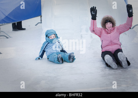 A woman and her daughter ride an ice slide at the Quebec Winter Carnival (Carnaval de Quebec) in Quebec city Stock Photo