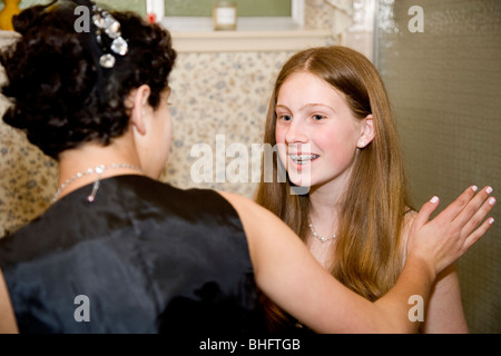 Preparing for their Formal Dance, five multi-ethnic girls putting on make up and doing their hair in the bathroom. Stock Photo