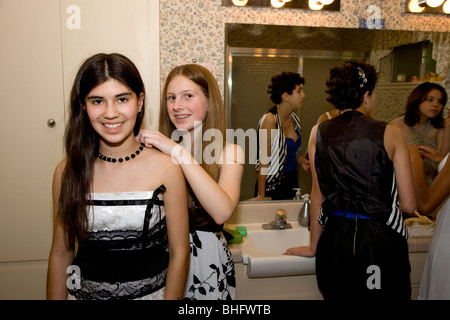 Preparing for their Formal Dance, five multi-ethnic girls putting on make up and doing their hair in the bathroom. Stock Photo