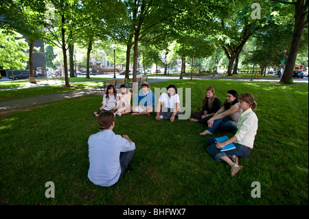 Teacher holding a class with students on lawn of campus Stock Photo