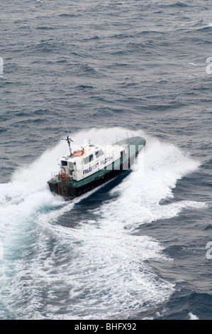 A pilot boat plows through a wave in a effort to deliver a port pilot to another ocean going vessel at Freeport in the Bahamas. Stock Photo