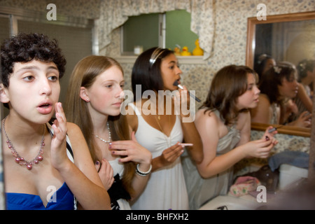 Preparing for their Formal Dance, five multi-ethnic girls putting on make up and doing their hair in the bathroom. Stock Photo