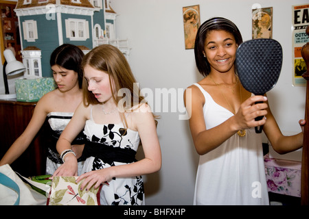 Preparing for their Formal Dance, five multi-ethnic girls putting on make up and doing their hair in the bathroom. Stock Photo