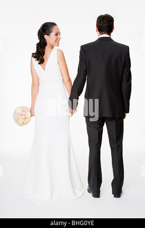 The bride and groom stand holding hands near the railing under the ...