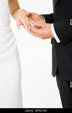 Groom placing a ring on brides finger Stock Photo