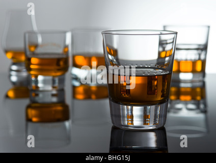 Five glasses with alcohol stand on glass. One glass in the foreground Stock Photo