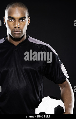 Serious footballer holding a ball Stock Photo