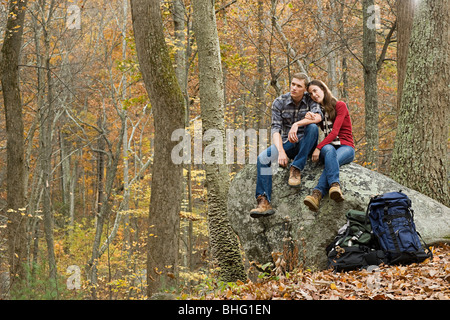 Young couple sitting on boulder in forest Stock Photo