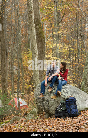 Young couple sitting on boulder in forest
