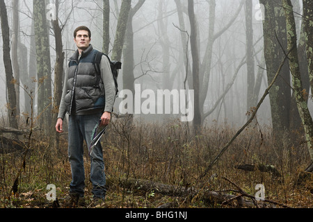 A male hiker standing in a misty forest opening Stock Photo