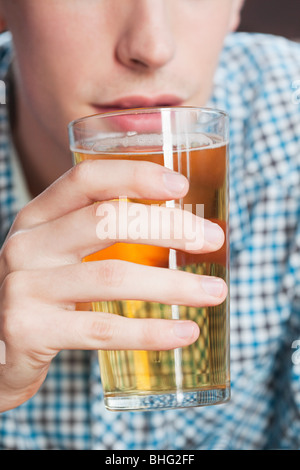 Young man drinking beer, close up