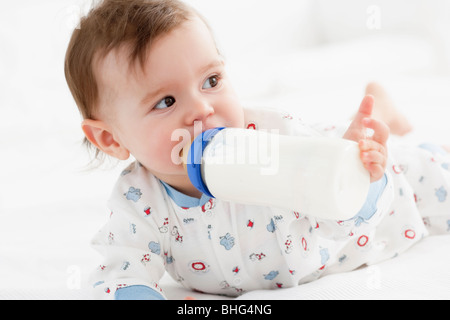 girl drinking bottle of milk laying on bed blond toddler Stock Photo - Alamy