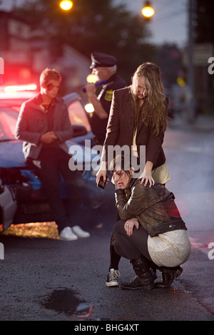 Young people and police officer at scene of car crash Stock Photo