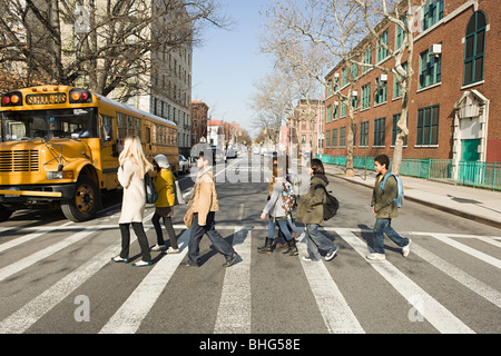 Teacher and pupils crossing road Stock Photo