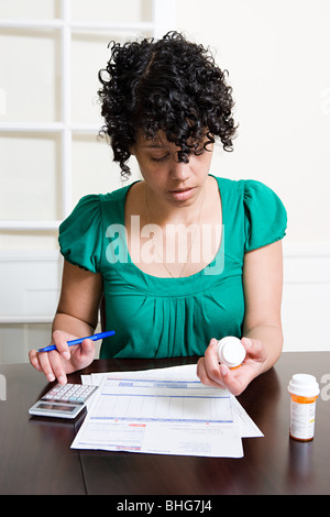 Woman with bills and tablets using calculator Stock Photo