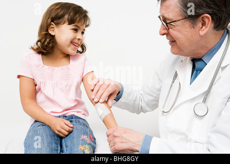 Doctor putting plaster on girl Stock Photo