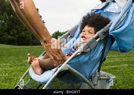 Parent reaching for baby in push chair