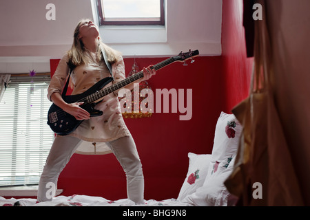 woman playing guitar on bed Stock Photo