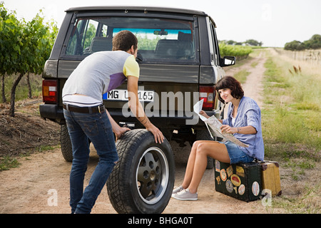 Couple by suv with tyre and map Stock Photo