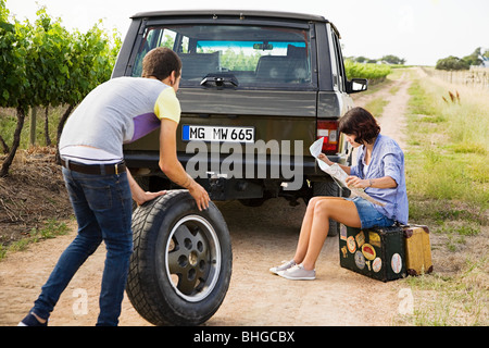Couple by suv with tyre and map Stock Photo