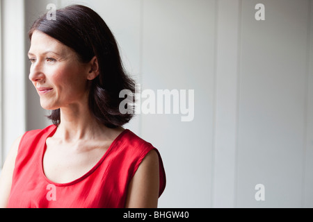 woman in red dress standing at window