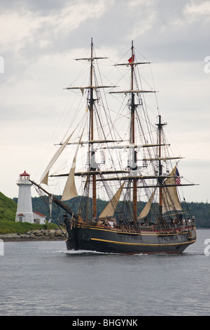The full rigged ship Bounty passes the lighthouse on Georges Island during the 2009 Tall Ships festival in Halifax, Nova Scotia. Stock Photo