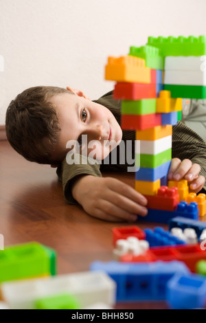 8 year old boy playing with colorful cubes on the floor Stock Photo