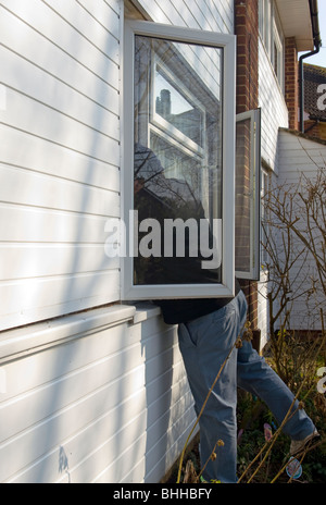 Burglar Leaning Through An Open Front Window (posed by model) Stock Photo