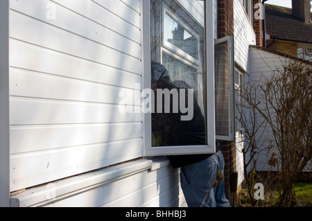 Burglar Leaning Through An Open Front Window (posed by model) Stock Photo