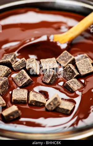 Wooden spoon stirring melting rich chocolate chunks Stock Photo