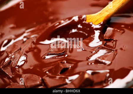 Wooden spoon stirring melting rich chocolate chunks Stock Photo