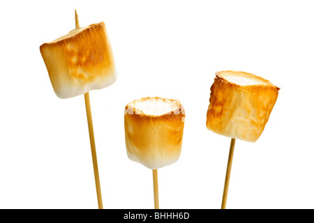 Three golden toasted marshmallows on wooden skewers Stock Photo