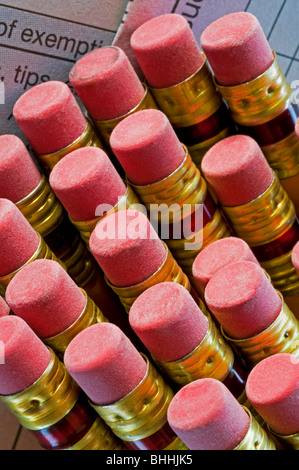 Tops of pencil eraser heads sitting on top of tax forms Stock Photo
