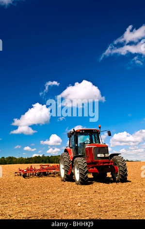 Small scale farming with tractor and plow in field Stock Photo