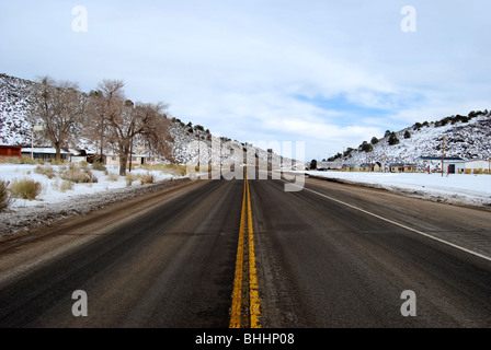 long paved and winding road with snow in landscape Stock Photo