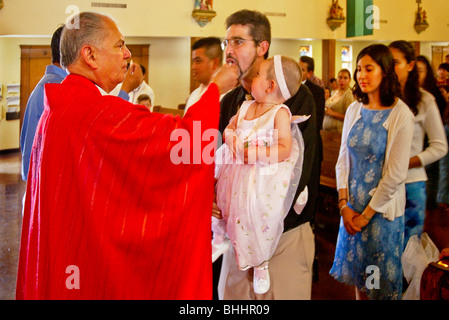 A priest offers communion at Mass to his mostly Hispanic parishioners in a Long Beach, California, Catholic church including a f Stock Photo