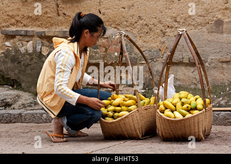 Chinese girl selling mangoes at Jianshui market in Yunnan, China Stock Photo