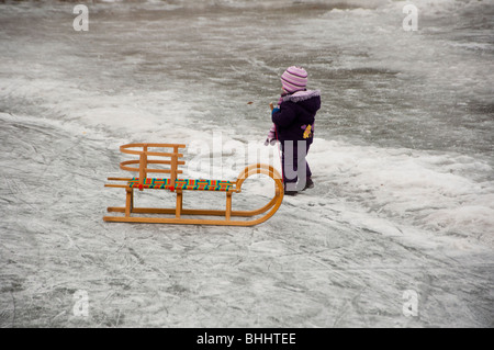 Little girl enjoying the frozen lake with her sledge Stock Photo