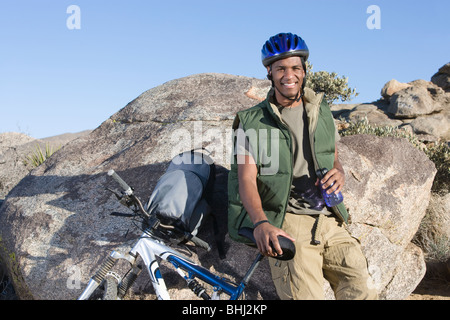 Man stands leaning against rock with mountain bike Stock Photo