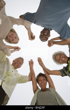 Senior friends hold hands and look down at camera Stock Photo