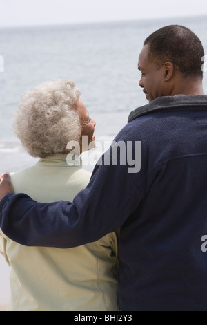 Man stands with his arm round a woman at waters edge Stock Photo