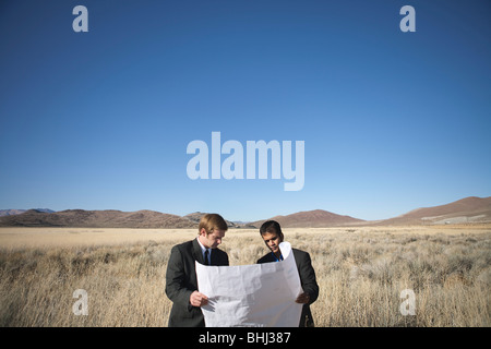 2 men examining blueprints in field Stock Photo