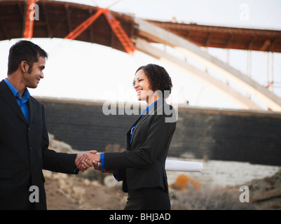 Man and woman on work site shaking hands Stock Photo