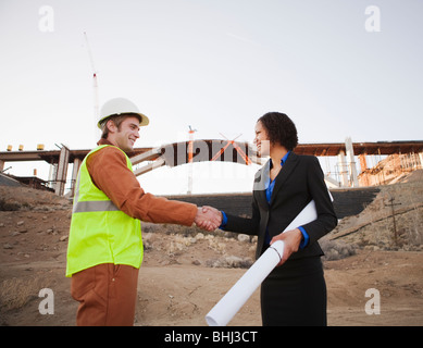 Man and woman on work site shaking hands Stock Photo