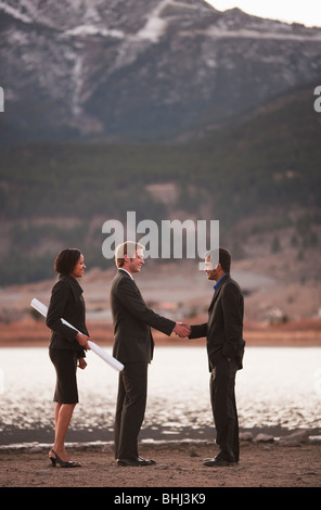 Couple with plans shakes hands with man Stock Photo