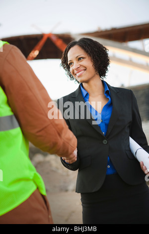 Woman shaking hands with man on worksite Stock Photo