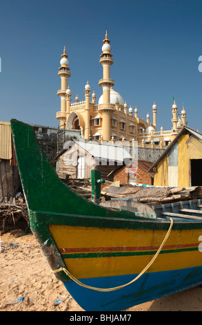 India, Kerala, Kovalam, Vizhinjam village colourful fishing boats on beach in front of mosque Stock Photo